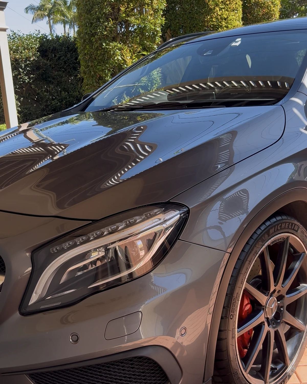Grey Mercedes after a detail, front three-quarter view on a brick driveway with reflections in the paint